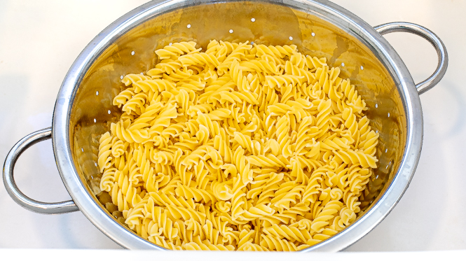 Rotini noodles being drained in a colander.