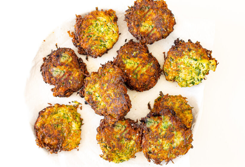 Zucchini fritters on a paper towel lined plate.