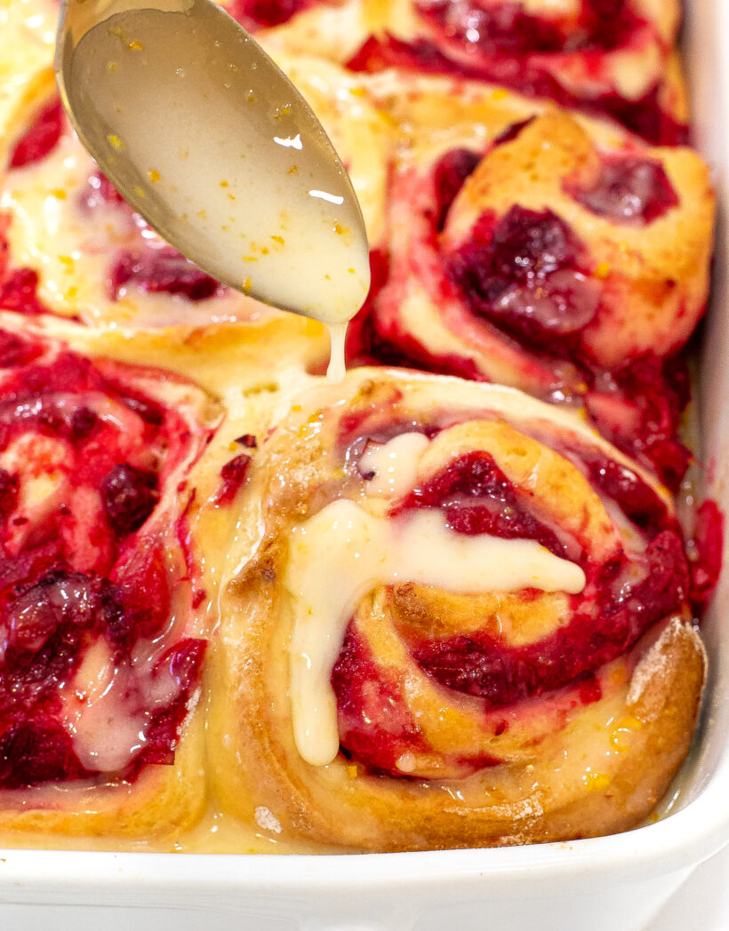 Orange glaze being spooned on top of a roll.