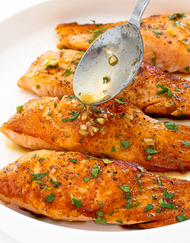 pouring pan sauce on top of pan seared salmon