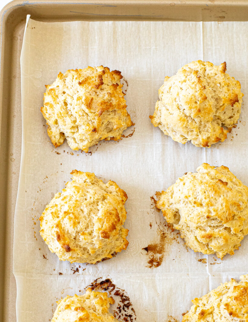 Overhead shot of drop biscuits on a baking sheet after being baked. 