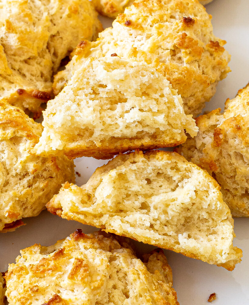 Drop biscuit broken in half to show the inside texture, surrounded by more biscuits. 