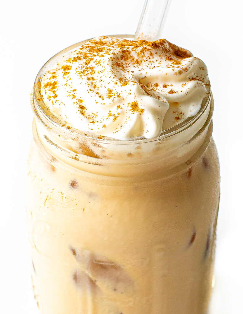 Banana bread latte in a glass with a straw.