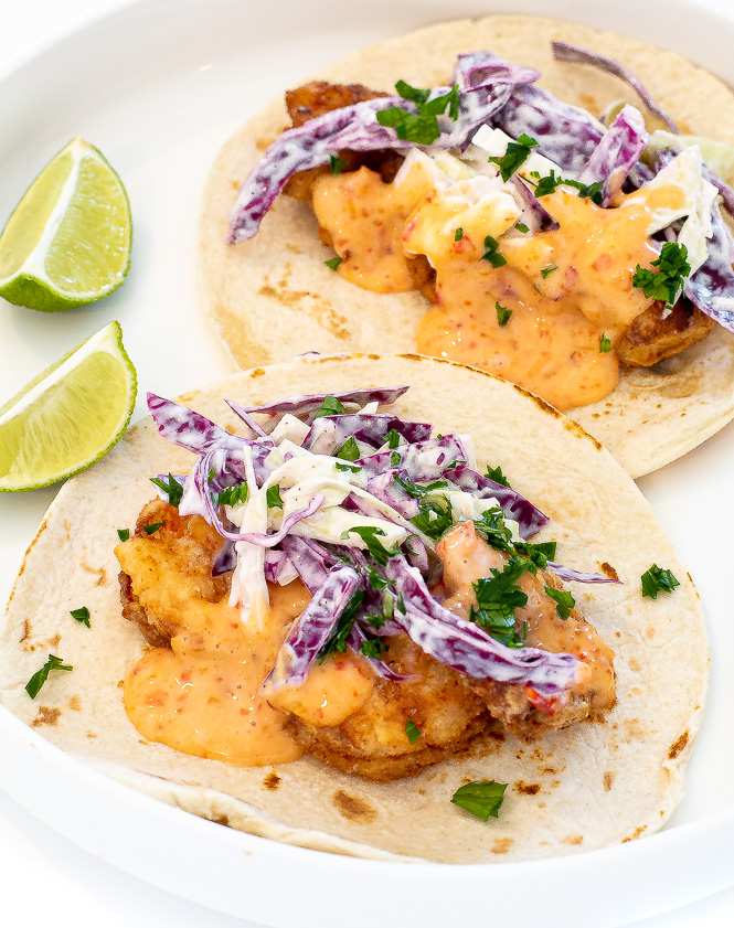 Bang bang shrimp tacos on a white plate. 