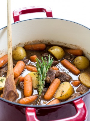 a closeup of this homemade Beef Stew in a dutch oven with fresh herbs, carrots, and potatoes | chefsavvy.com