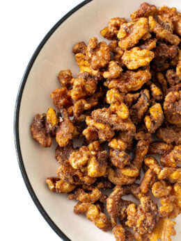 Candied walnuts in a white bowl with a black rim.