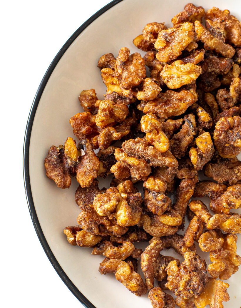 Candied walnuts in a black rimmed white bowl.