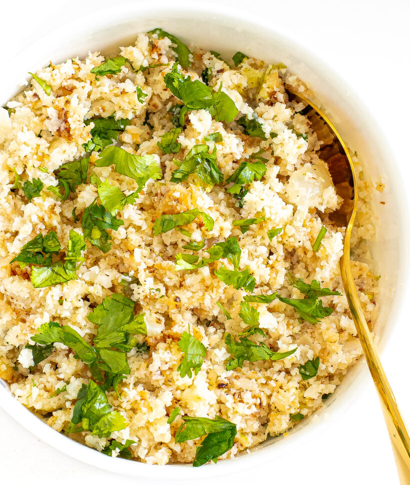 Cilantro lime cauliflower rice served in a bowl with a gold spoon.