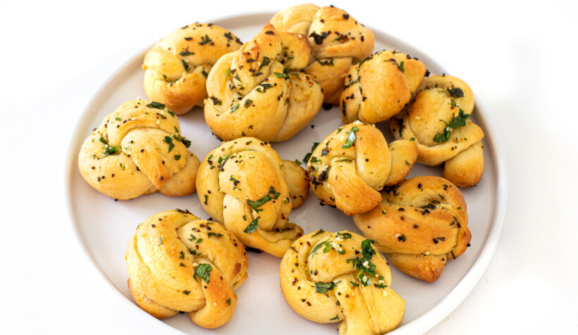 Baked garlic knots served on a white plate.
