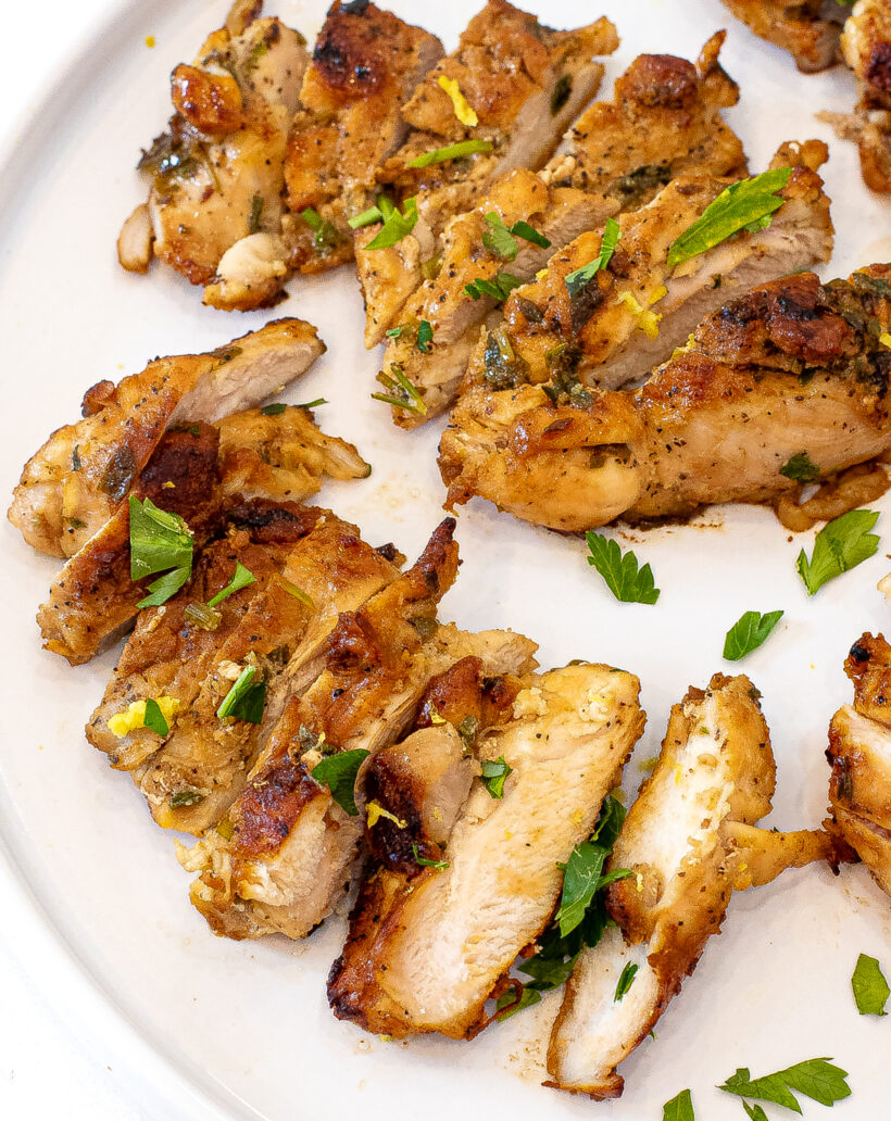 Chicken thighs sliced into pieces on served on a white plate. 