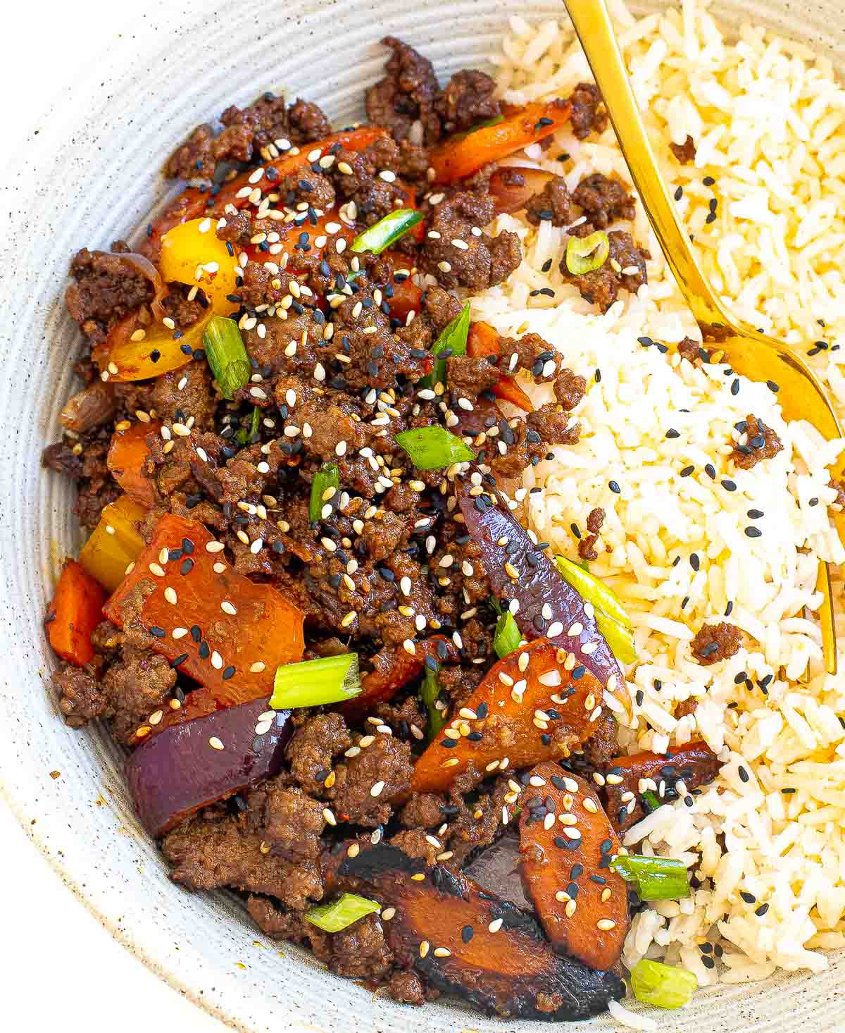 ground beef stir fry with veggies over rice on a bowl