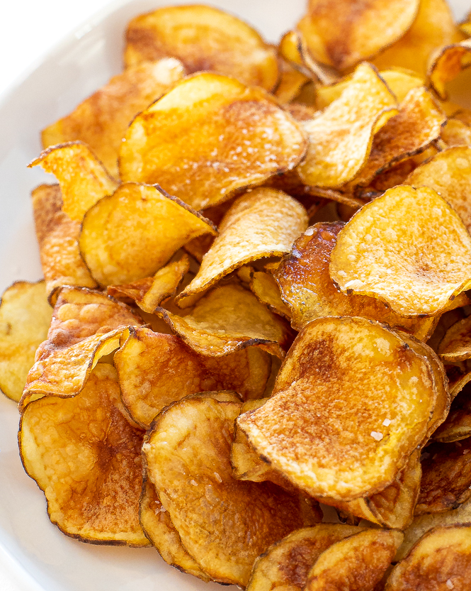 Up close shot of potato chips in a white bowl.