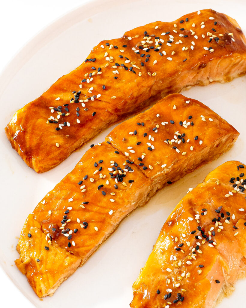 honey sriracha salmon on white plate with tuxedo sesame seeds on top