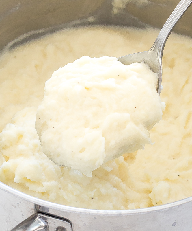scooping creamy mashed potatoes out of large pot