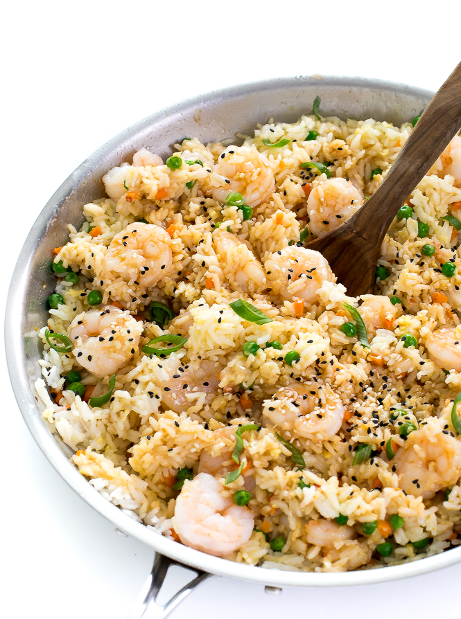 Shrimp fried rice in a large skillet with a wooden spoon.