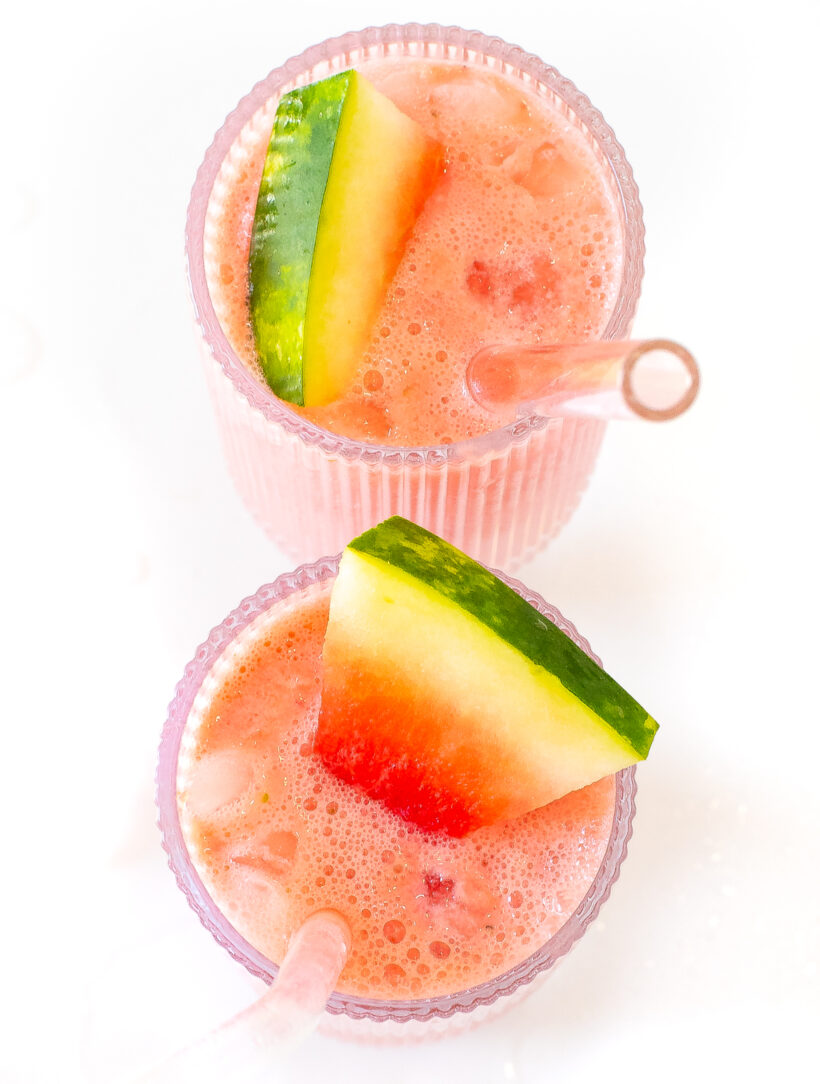 Two glasses of watermelon smoothie garnished with slices of watermelon.