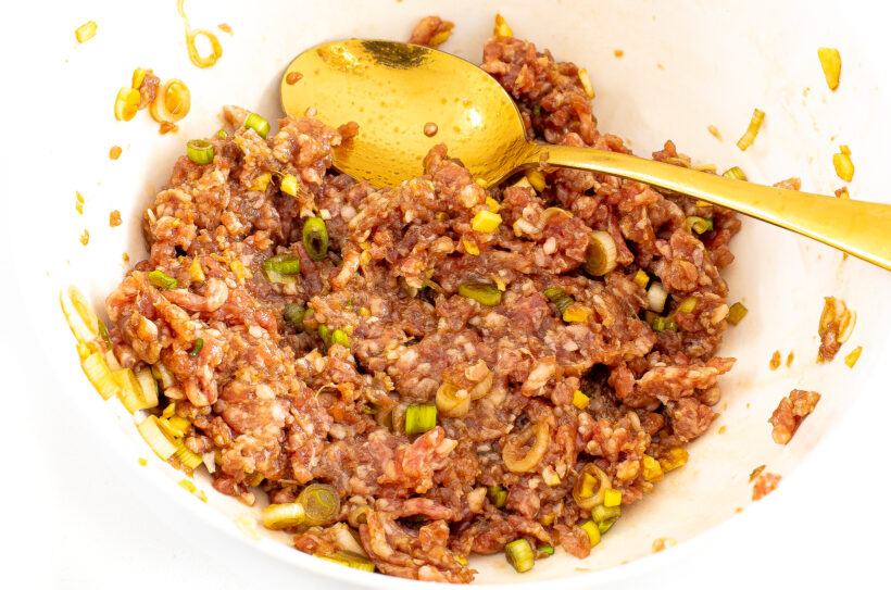 White mixing bowl filled with wonton filling.