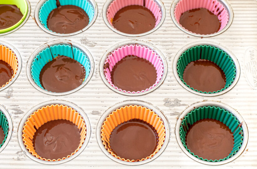 Top chocolate layer placed on top of the peanut butter cups in a muffin tin.