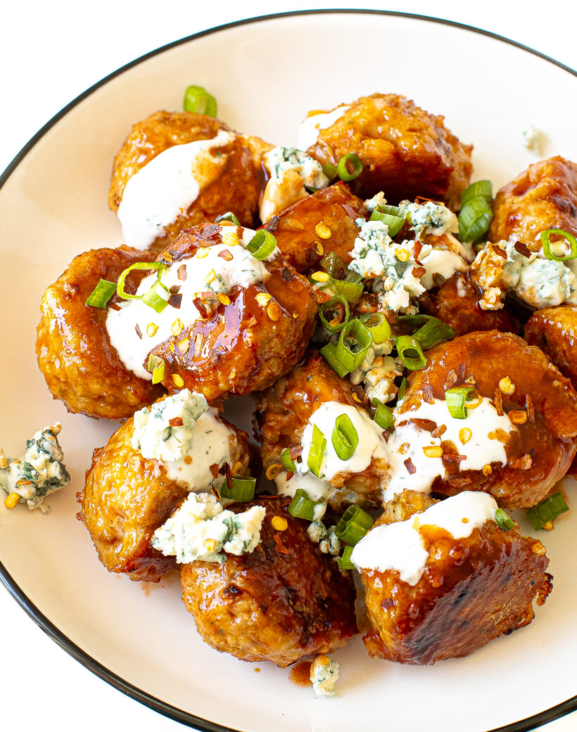 Firecracker meatballs with toppings on a white plate.