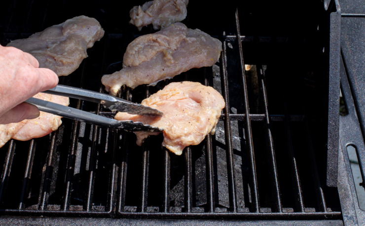 flipping grilled chicken on grill