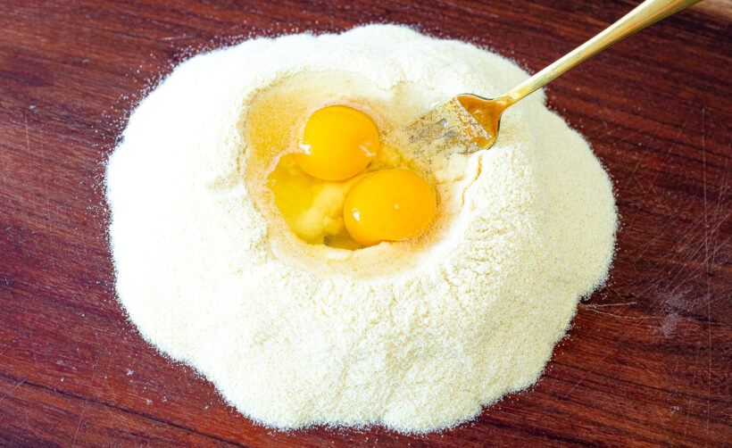 Eggs placed in a mound of flour.