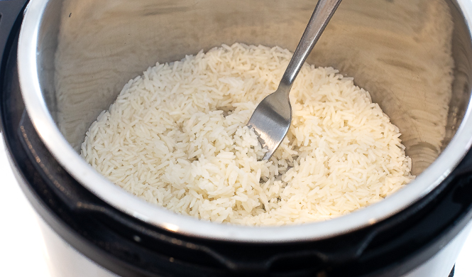 Rice being fluffed with a fork in an instant pot.