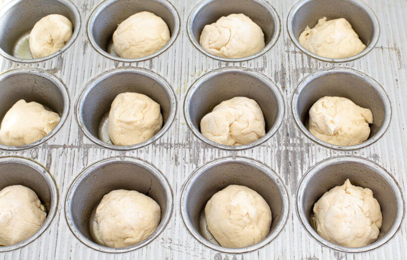 Focaccia dough divided into muffin tin before the dough has risen. 