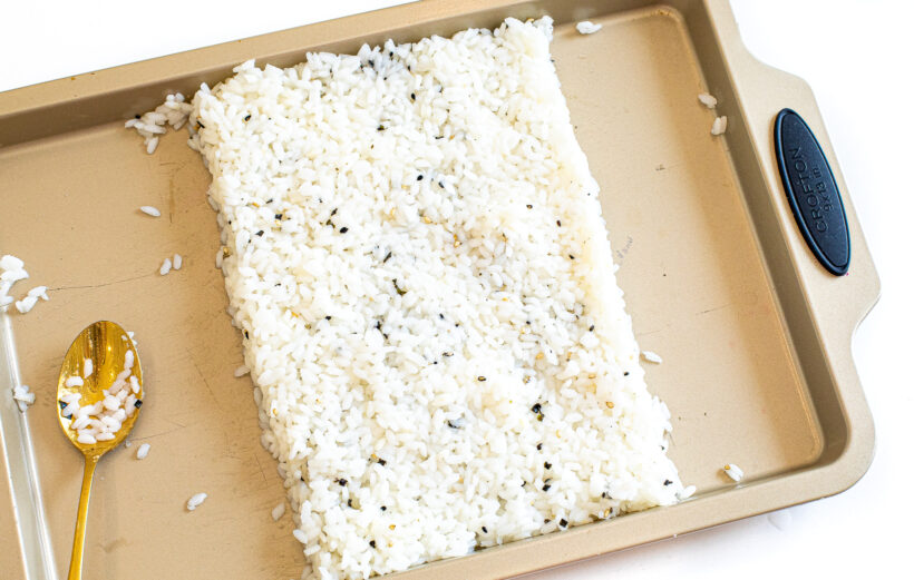 Sushi rice pushed into a rectangle on a sheet pan. 