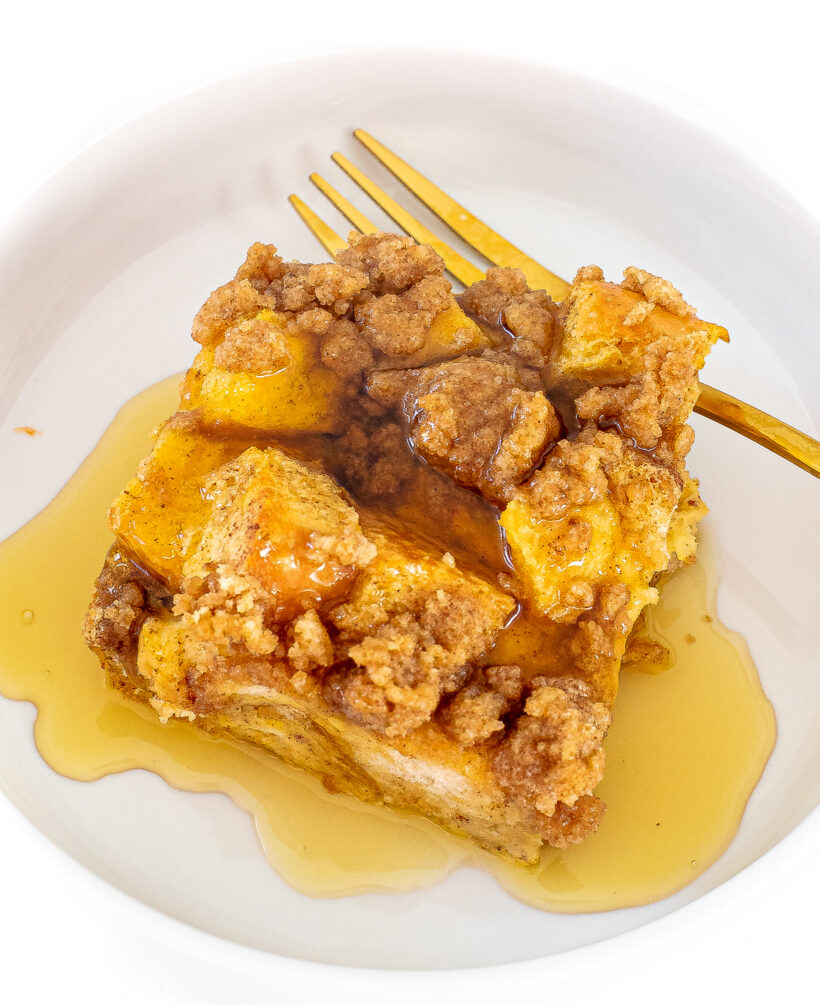 A slice of eggnog casserole topped with maple syrup on a white plate.