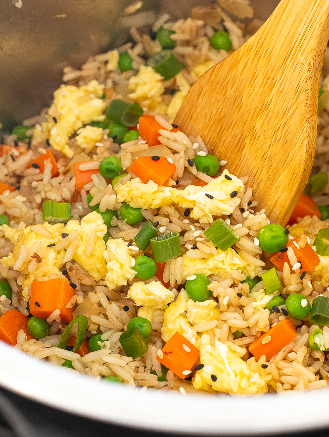 Close up shot of fried rice being stirred by a wooden spoon.