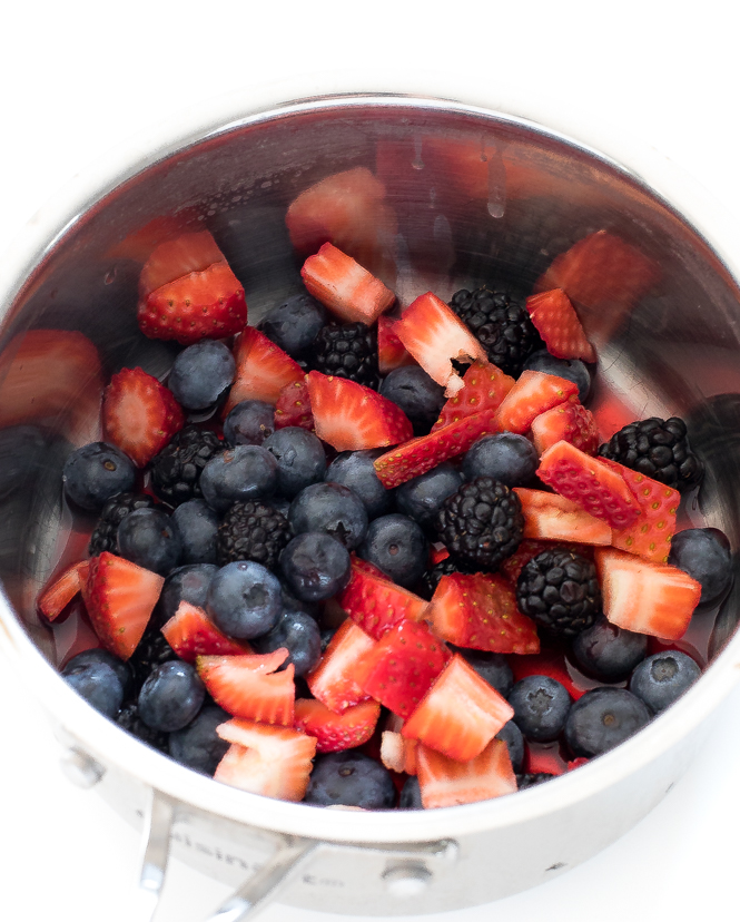 Saucepan filled with strawberries, raspberries, and blueberries.