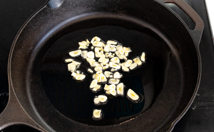 Sliced garlic and peanut oil in a skillet.