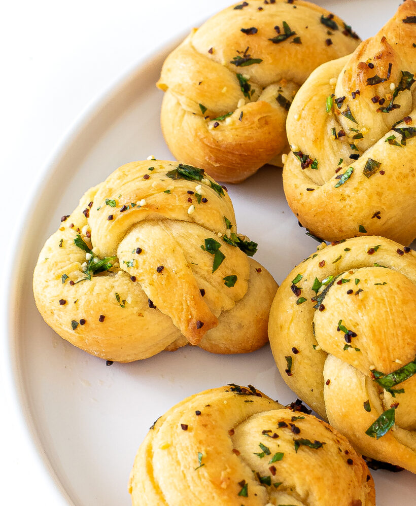 Baked garlic knots served up on a white platter.