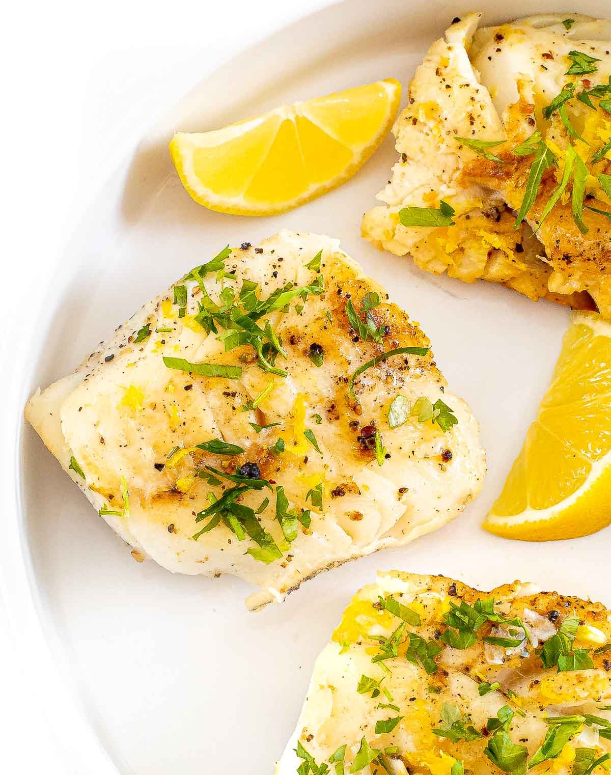 lemon garlic cod on white plate with lemon slices