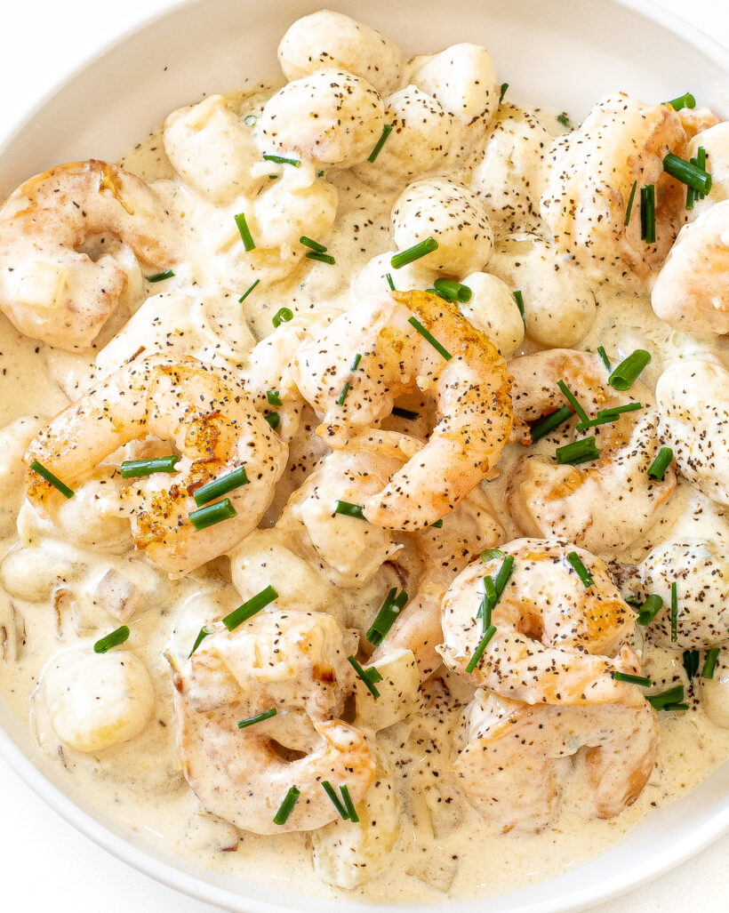 Creamy gorgonzola gnocchi and shrimp serve in a white bowl.