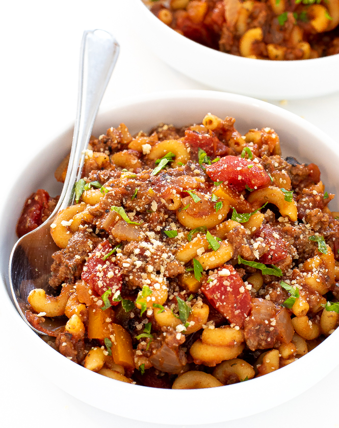 Goulash in a white bowl with a silver spoon and another bowl in the background.