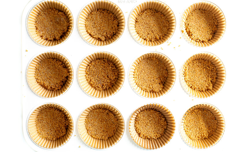 Graham cracker crust added to muffin tin.