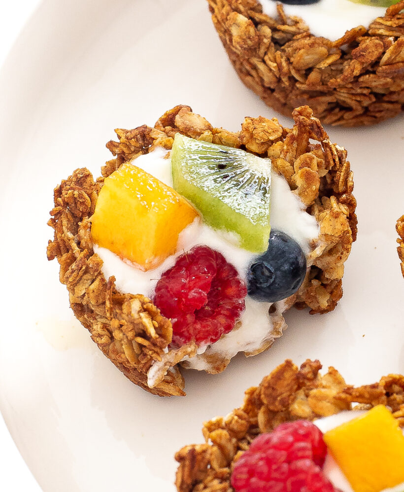 Granola cup with a bite taken out of it on a white plate.