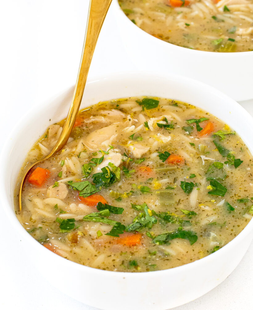Two white bowls filled with lemon chicken orzo soup. 