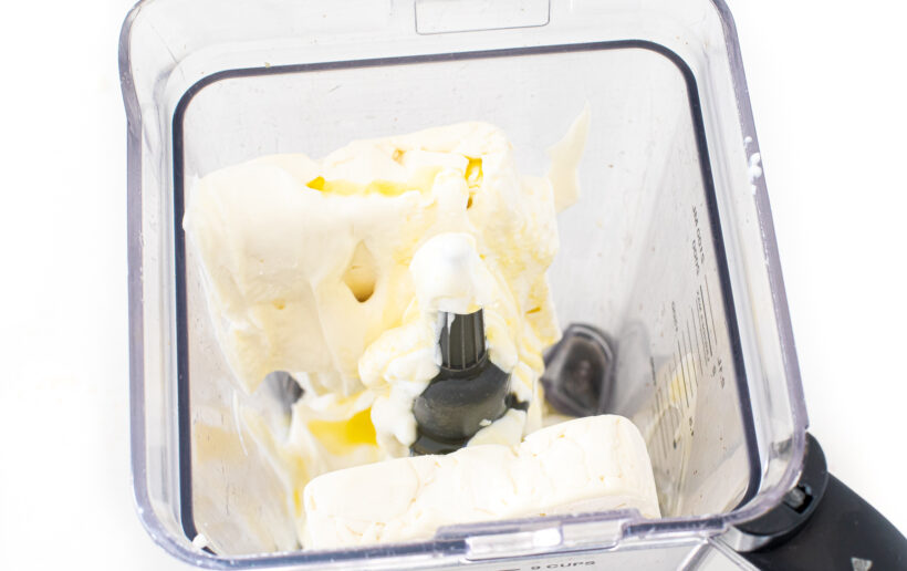 A blender with ingredients for feta dip.