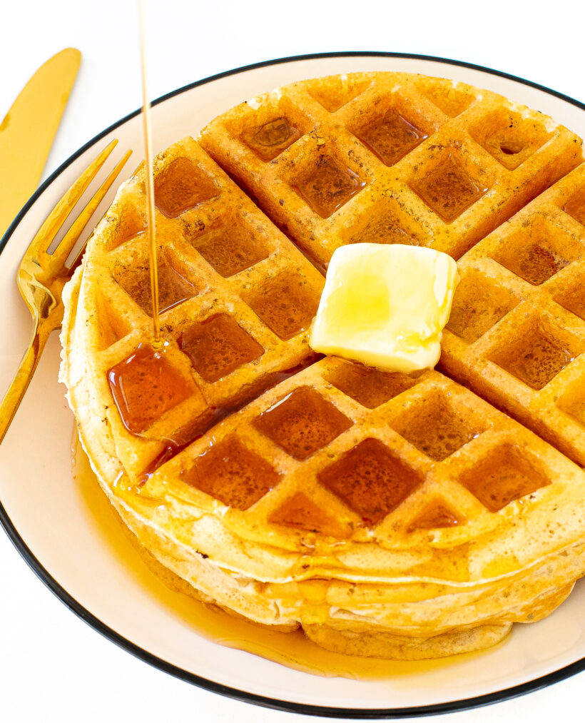 author pouring maple syrup onto waffles