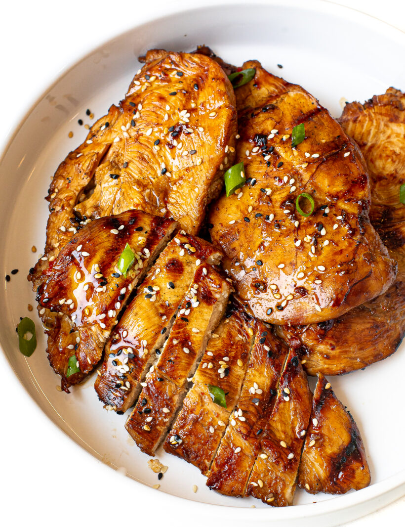 overhead shot of grilled asian chicken topped with sesame seeds and green onions