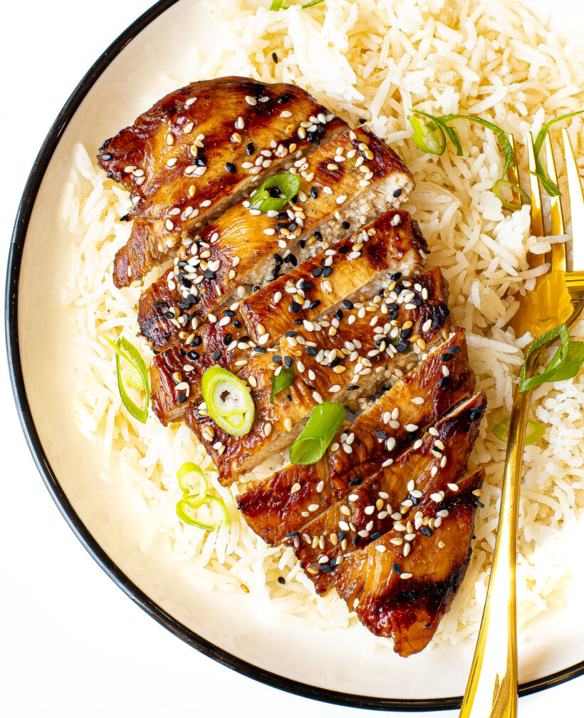 white rice on a plate topped with sliced grilled asian chicken