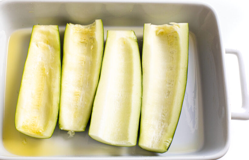 Zucchini halves in a baking dish.