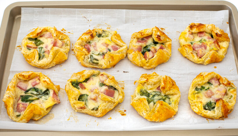 Ham and cheese puff pastry on a baking sheet after being baked. 