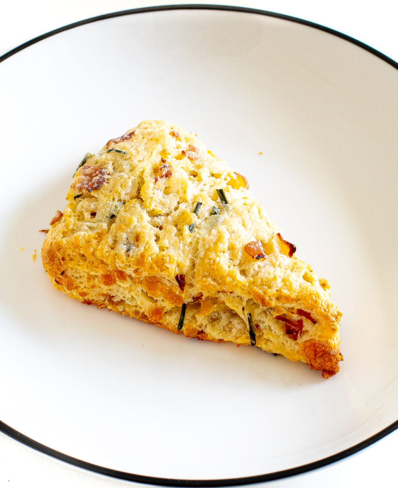 Overhead shot of a ham and cheese scone on a white plate. 