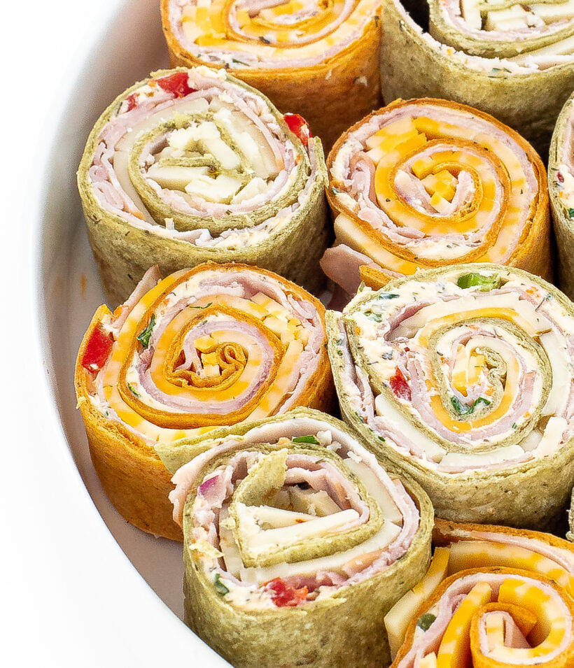 Ham and cheese pinwheels lined up next to each other on a serving dish.