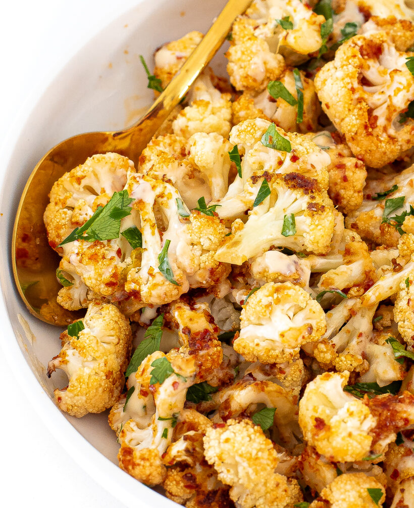 Cauliflower with harissa and tahini being served in a white platter.