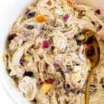 A white bowl with harvest chicken salad. A gold spoon is in the salad.
