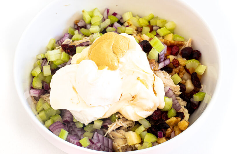 Ingredients for harvest chicken salad in a white bowl.